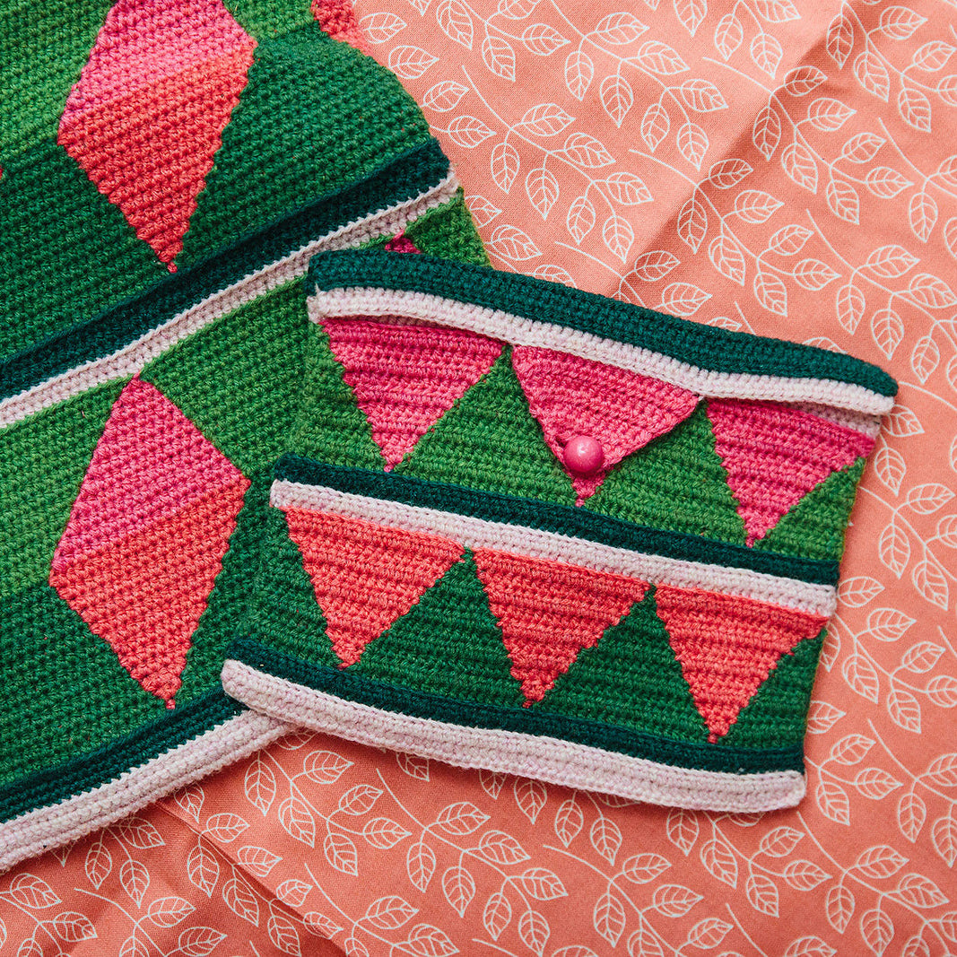 Crocheted green and pink patterned bag on a pink fabric background